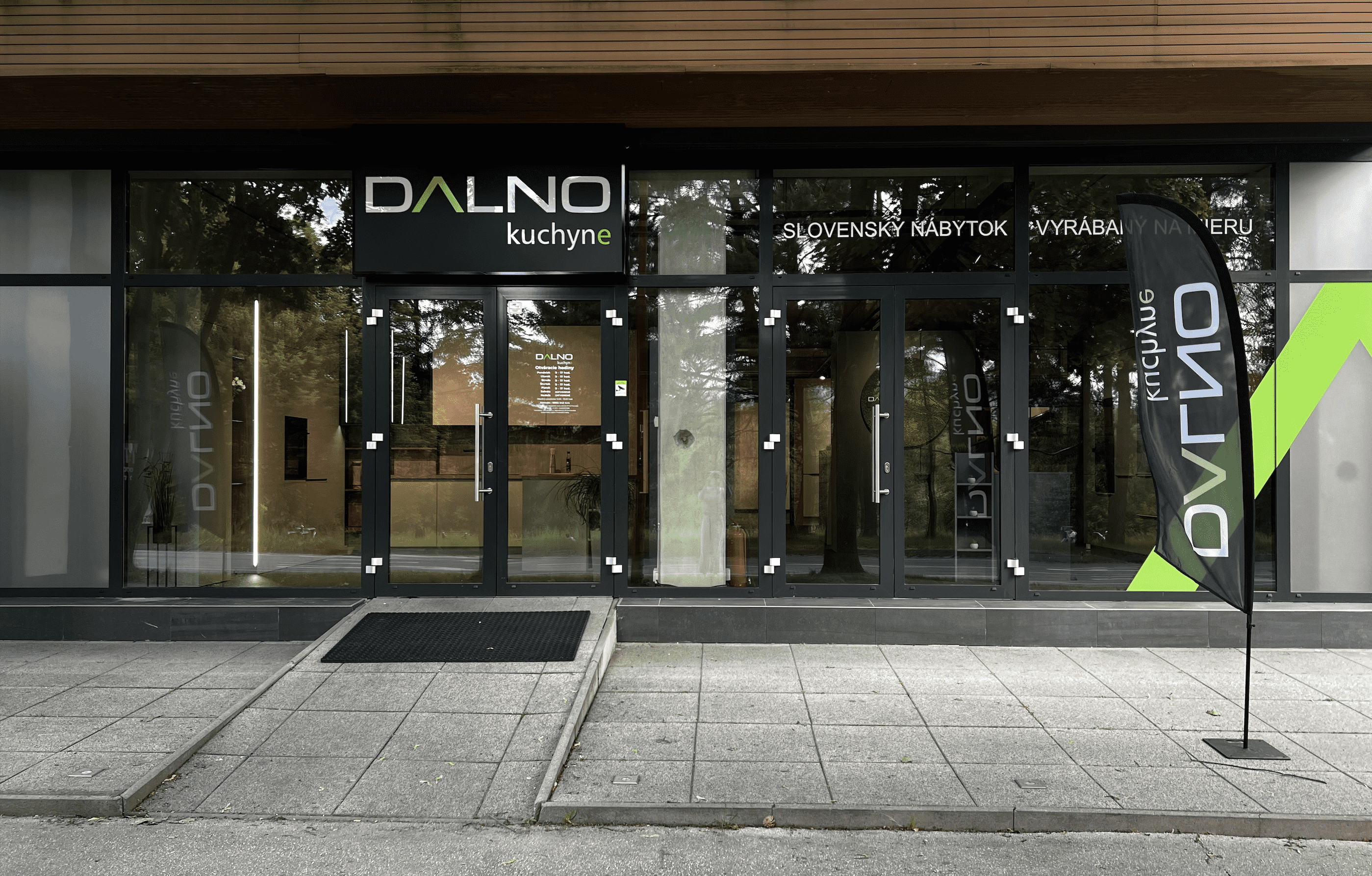 Exteriér showroomu Dalno Prievidza s moderným dizajnom budovy, presklenými stenami a logom značky na fasáde. Pred vstupom je upravená zeleň a viditeľné parkovacie miesta.